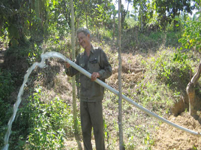 Ông Phan Chạng đang tưới nước cho vườn cây.